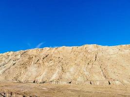 A mountain of wet yellow sand and a blue, clear sky photo