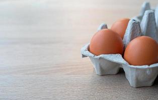 Closeup on carton of three fresh brown free range eggs photo