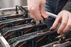 Man's hands connecting a new graphics card to mining farm. IT equipment. Cryptocurrency business. photo