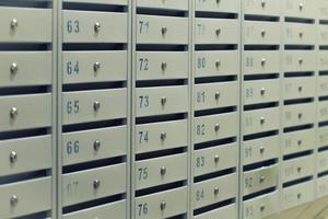 Many posting metal mailboxes with room number at residential building photo