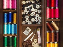 Sewing tools and multi colorful threads in wooden box, flat lay picture photo