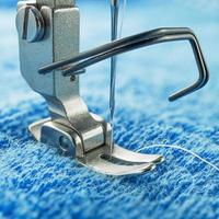 sewing machine parts are as follows needle and presser foot on blue fabric photo