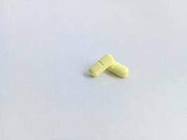two small yellow pills or pills isolated on a white background or on white paper photo