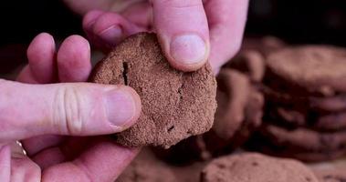 brown chocolate cookies are broken by hands into several pieces photo