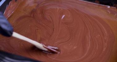 mixing liquid molten chocolate with half a spoon and dripping chocolate on top photo