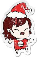 distressed sticker cartoon of a laughing vampire girl wearing santa hat vector