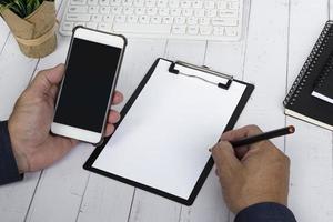 Businessman writing Today's Meeting Agenda with holding a smartphone. photo