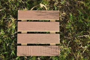 View of empty wooden frame laying on green grass background. Copy space. photo