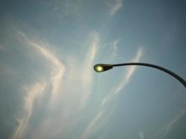 The street lights are on and you can see the blue sky and clouds above photo