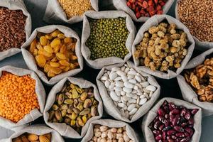 Colourful various beans in cloth sacks. Uncooked assorted legumes. Mulberry, buckwheat, pistache, raisins, almond, garbanzo, others. Healthy cereals. photo