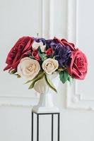 Shot of tender magnificent bouquet of roses on flower stand against white background in banquet hall used as decoration. Wedding flowers photo