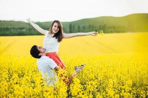 Portrait of happy young family couple feel happiness and freedom, pose together at yellow meadow against blue sky, demonstrates positiveness and true relationship. Romantic young people outdoor photo