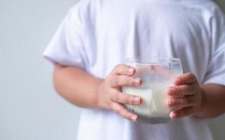 Kid 4-5 years old holding white milk in the glass isolated on white background,Daily life health care Medicine food photo