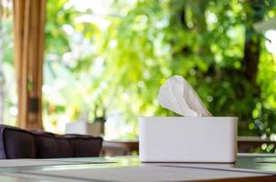 White tissue paper with tissue box on the wooden table in restaurant at breakfast time and nature blure background photo