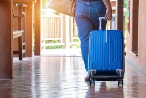 mujer arrastrando una maleta para salir de la habitación de vacaciones, concepto de viaje y estilo de vida, vista trasera foto