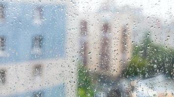 gotas de lluvia en la ventana y casas de apartamentos borrosas foto