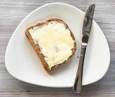 sandwich with butter and knife on plate on table photo