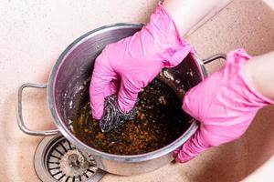 hands scrub stewpan with burnt food by sponge photo