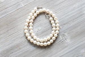 collar de perlas blancas sobre tabla de madera gris foto