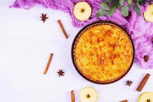 Delicious homemade apple pie on pink background. Apple pie with ingredients, apples and cinnamon. Top view photo