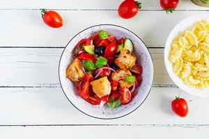 Traditional italian salad Tuscan Panzanella with tomato, bread and pickled olives photo