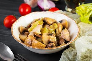 Stew chicken thighs with mushrooms, celery, onion and pepper. Stir fry chicken on wooden background photo