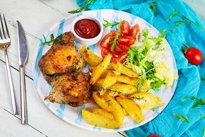 delicioso pollo al horno con patatas sobre fondo de madera foto