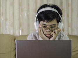 colegial preadolescente usando auriculares para aprender en línea viendo la lección de clase mirando la computadora portátil para estudiar. el aprendizaje a distancia y la educación se quedan en casa. foto