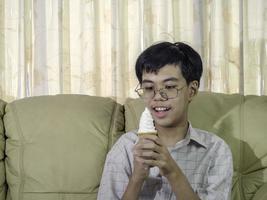 niño de asia niño sostenga helado de vainilla en cono de gofres feliz sonriendo y comiendo deliciosamente en verano con diversión y buen humor. foto