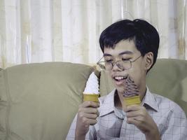 niño de asia niño sostenga helado de vainilla en cono de gofres feliz sonriendo y comiendo deliciosamente en verano con diversión y buen humor. foto