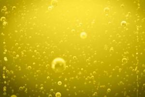 Defocus blurred transparent yellow colored clear calm water surface texture with splashes and bubbles. Pouring beer with bubble froth in glass for background on side wave curve shape texture foam. photo