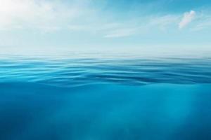 superficie azul del agua del mar o del océano y bajo el agua con cielo soleado y nublado foto