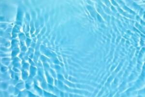 desenfoque borroso transparente color azul claro agua tranquila textura superficial con salpicaduras y burbujas. fondo de naturaleza abstracta de moda. onda de agua a la luz del sol con espacio de copia. textura de acuarela azul foto