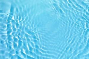 Defocus blurred transparent blue colored clear calm water surface texture with splashes and bubble. Trendy abstract nature background. Water wave in sunlight with copy space. Blue watercolor texture photo