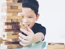 Vintage tone of asian kid is playing wood blocks tower game for practicing physical and mental skill. Photo is focused is hands.