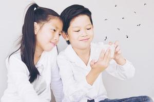 una encantadora pareja asiática de niños de la escuela se está tomando selfie, de 7 y 10 años, sobre fondo gris foto