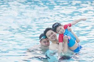 Father and his two son play in clear water swimming pool - happy family play time concept photo