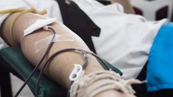 Volunteer man giving blood donation to cross red organisation - people with blood donation concept photo