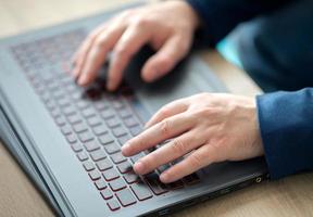 Male hands are typing on a laptop keyboard. A man in the office works writes on a laptop. Selective focus photo