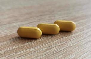 Three pills, dietary supplements on wooden table photo