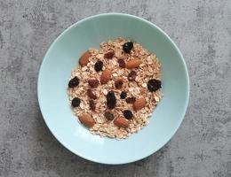 Bowl of raw, whole oatmeal with raisins and almonds nuts photo