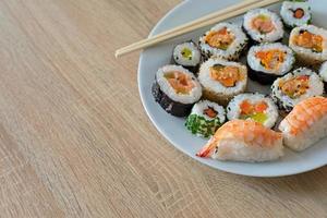 Closeup on sushi set of maki with chopsticks on a white plate photo