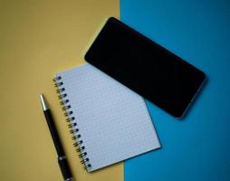 Office workplace minimal concept. Blank notebook with pencil, mobile phone photo