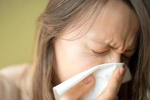 Having a cold or corona virus flu symptoms. Young woman with a an allergy sneezing into her handkerchief to prevent spread the disease for immunity photo