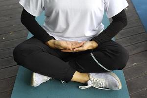 Close up of woman making yoga exercises sitting on a mat outdoors photo