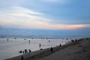 Pangandaran, West Java Indonesia Mei 8 2022 Beach atmosphere while on vacation, lots of people on the beach, swimming in the sea in the morning photo