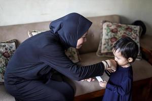 tradición del pueblo indonesio durante la celebración de eid mubarak de distribuir dinero o llamada thr. mujer musulmana asiática da dinero a una linda chica de familia durante idul fitri. foto