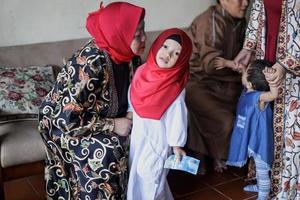 Grandmother kissing granddaughter's cheek during lebaran idul fitri day. photo