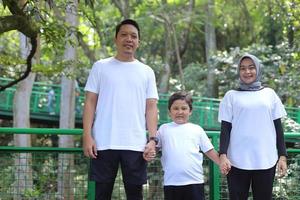 Young happy family of three having fun together outdoor. Parents holding hands with son look happy and smile. Happiness and harmony in family life. Family fun outside. photo