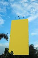 Blank yellow billboard mockup under beautiful sky. photo